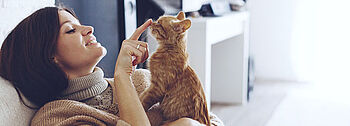 Schadstoffe im Haus Symptome: Frau mit Katze auf Sofa