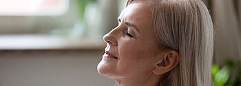 Trockene Luft in Wohnräumen: Ältere Frau atmet entspannt ein