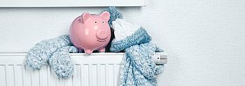Heizkurve einstellen lassen und bares Geld sparen Heizkurve einstellen: Sparschwein und Schal auf Heizkörper
