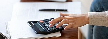 kWh berechnen kWh berechnen: Frau bedient Laptop und Taschenrechner
