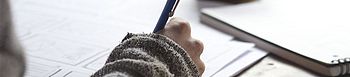 Fördermittel für die Heizung: Welche gibt es? Fördermittel für die Heizung: Person schreibt am Schreibtisch