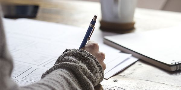 Fördermittel für die Heizung: Person schreibt am Schreibtisch
