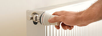 Thermostat Heizung defekt: Hand dreht an Heizungsthermostat