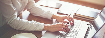 Online-Tool Fördermittelauskunft: Frau tippt auf Laptop an Schreibtisch