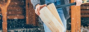 Holzvergaserheizung: Mann spaltet Holzscheit mit Axt