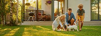 Heizen mit Erdwärme Heizen mit Erdwärme: Familie mit Hund spielt im Garten