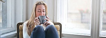 Trockene Heizungsluft Symptome: Frau trinkt Tee