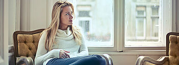 Heizung wird nicht richtig warm: Frau sitzt am Fenster