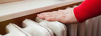 Heizung verliert Druck: Frauenhand auf Heizkörper