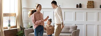 Glückliche Familie tanzt im Wohnzimmer mit Fußbodenheizung