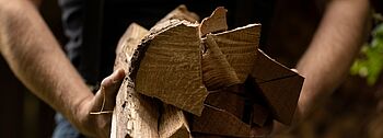 Die Scheitholzheizung: Ein kleiner Ratgeber Scheitholzheizung: Person mit Holzscheiten