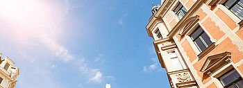 Lohnt sich Photovoltaik auch für Sie? Lohnt sich Photovoltaik: Hohe Altbau-Gebäude werden im Hintergrund und ein sonniger blauer Himmel.