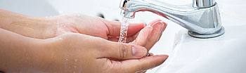 Durchlauferhitzer entkalken: Frauenhände unter Wasserhahn