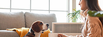Radiator, Konvektor und Flächenheizung im Überblick Radiator: Frau sitzt mit Hund vor mobiler Radiatorheizung