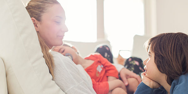 Wie heizt man richtig? Frau und zwei kleine Kinder auf Couch