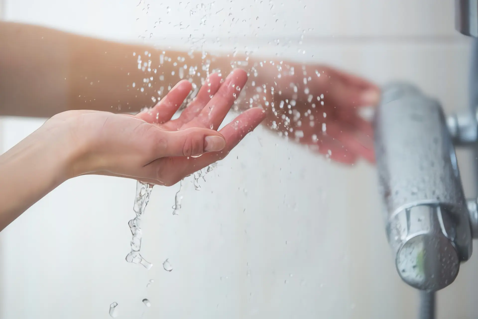 Durchlauferhitzer Kosten: Hände stellen Wassertemperatur ein