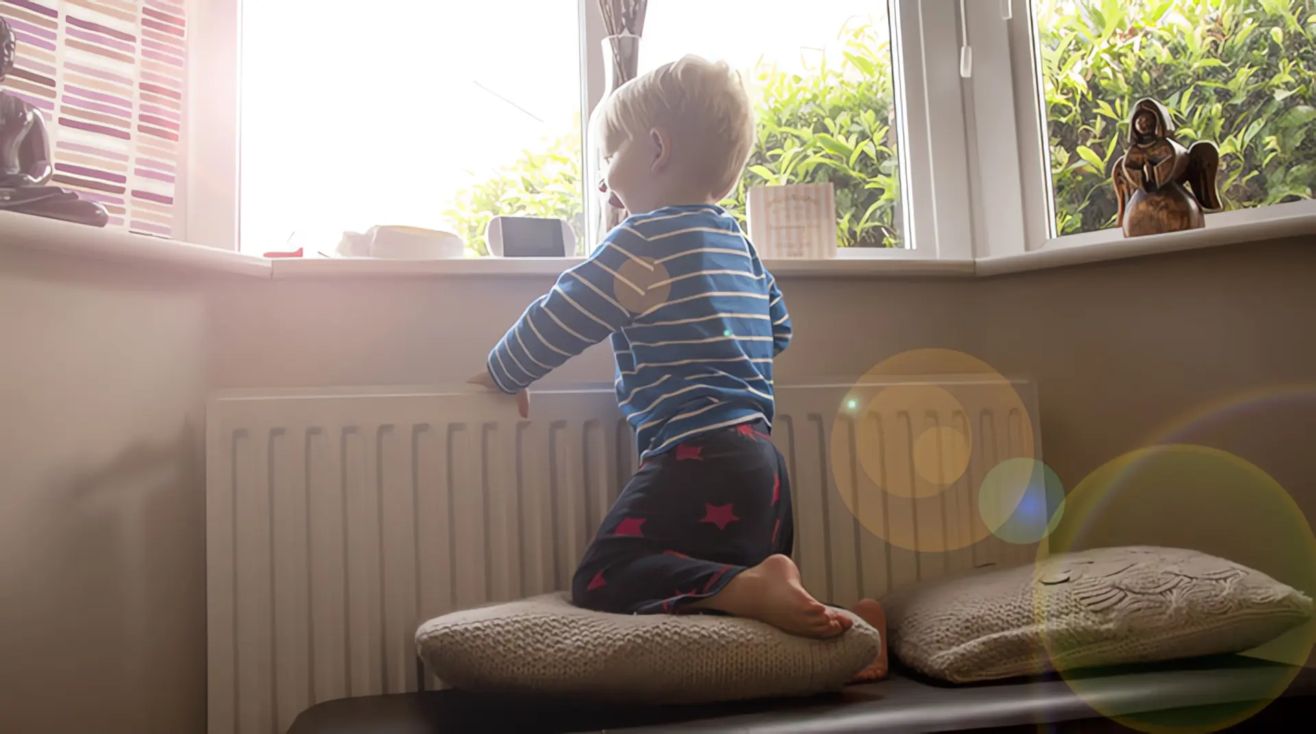 Heizen mit Fernwärme: Kleiner Junge an Fenster