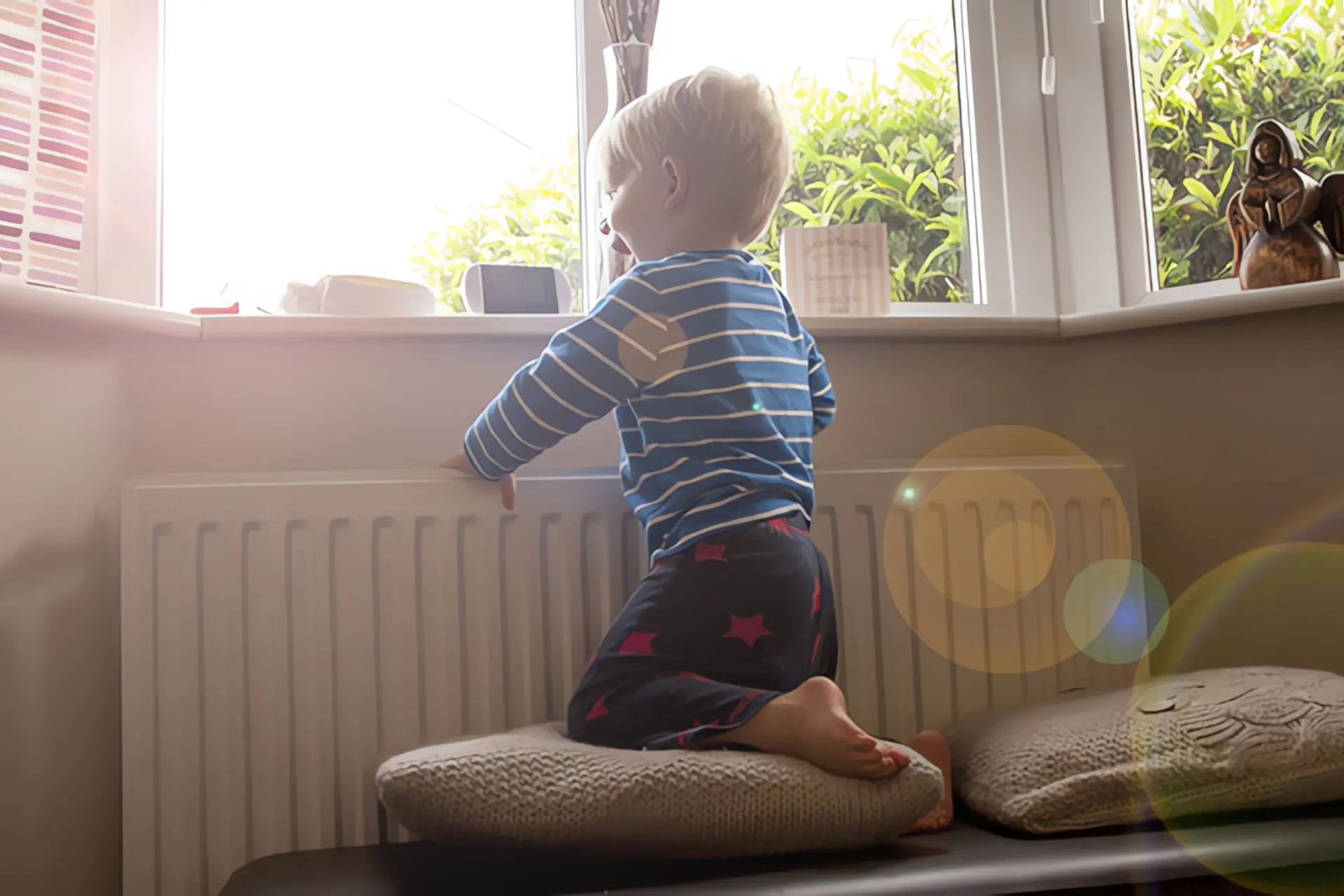 Heizen mit Fernwärme: Kleiner Junge an Fenster