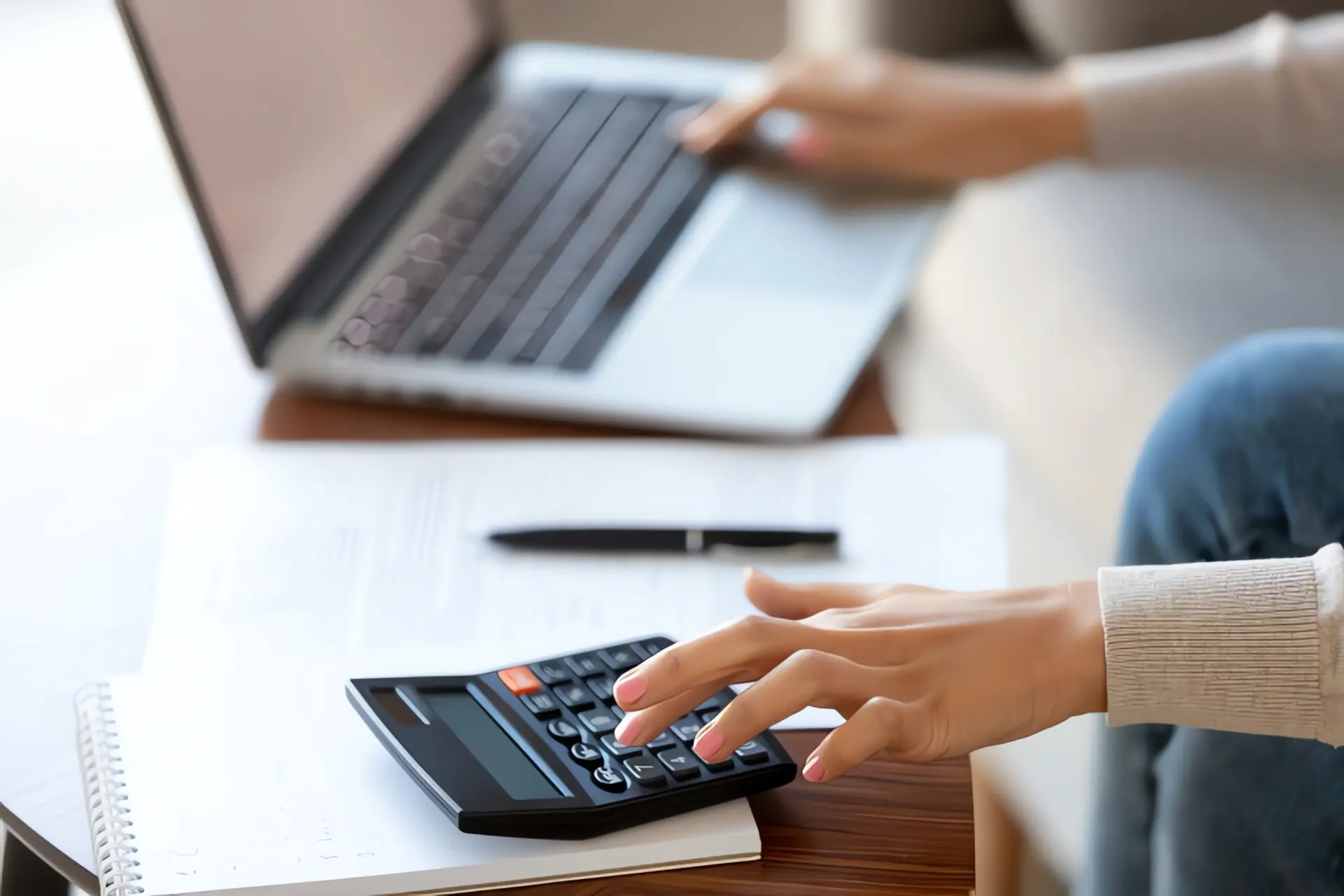 kWh berechnen: Frau bedient Laptop und Taschenrechner