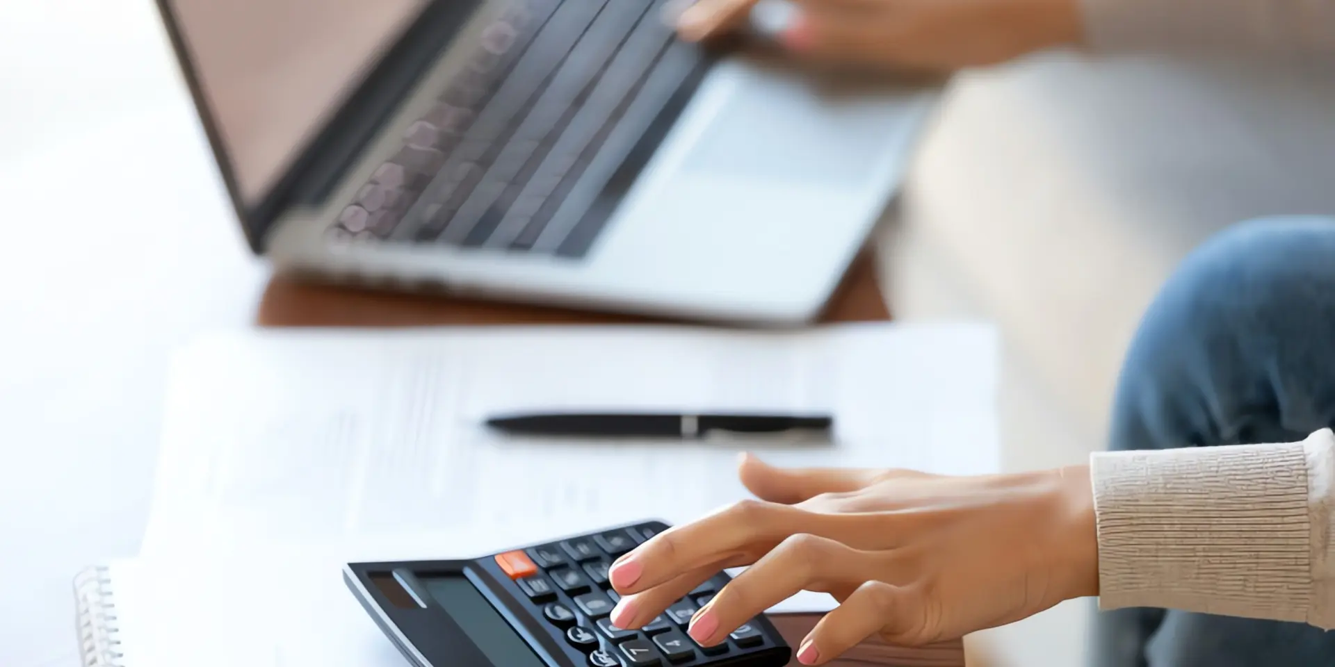 kWh berechnen: Frau bedient Laptop und Taschenrechner