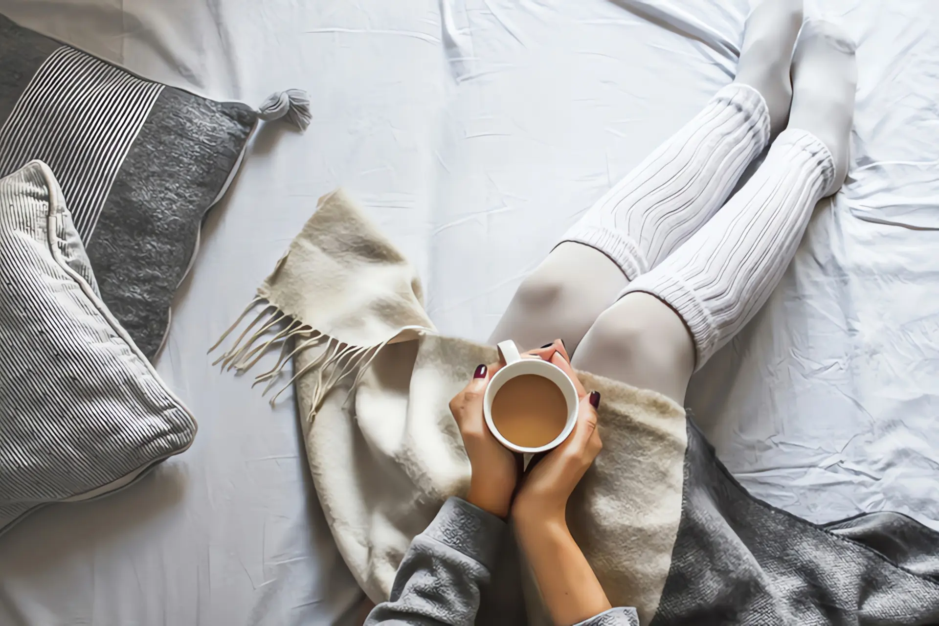 Nachtspeicherheizung wird nicht warm: Frau wärmt sich mit Kaffee und Wolldecke