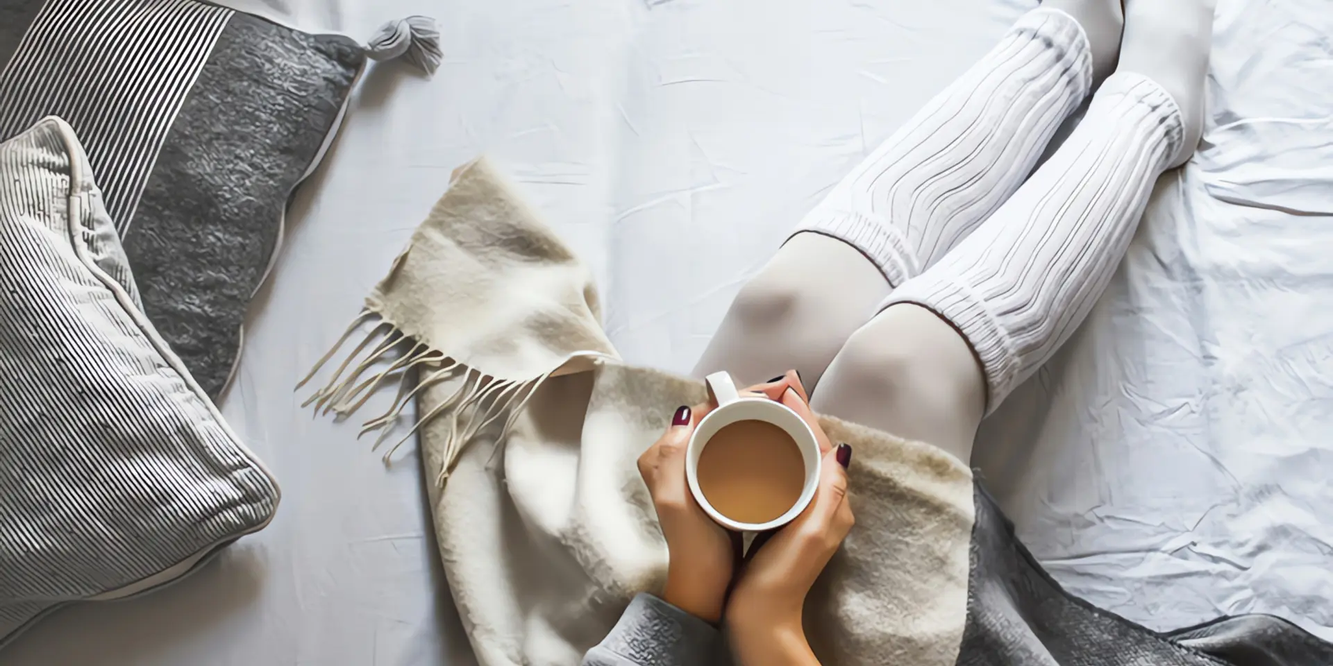 Nachtspeicherheizung wird nicht warm: Frau wärmt sich mit Kaffee und Wolldecke