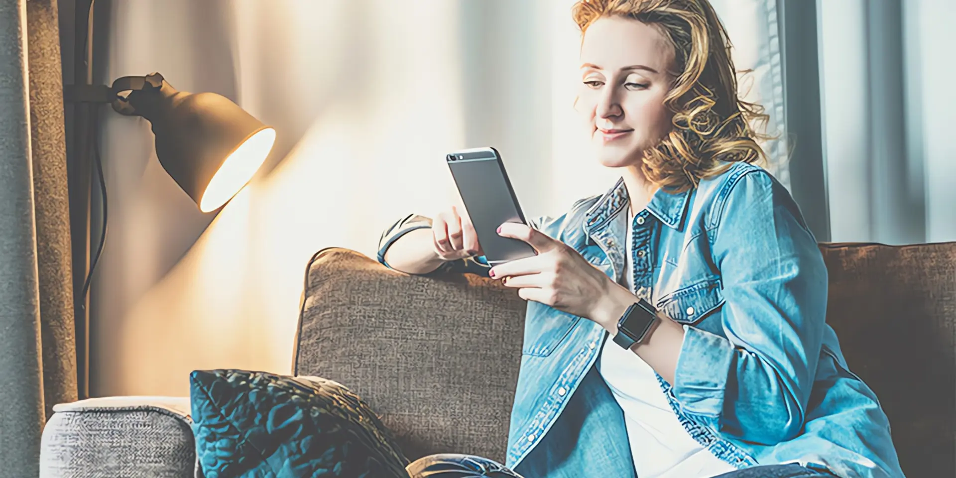 Smarthome Heizung: Frau sitzt mit Smartphone auf Couch