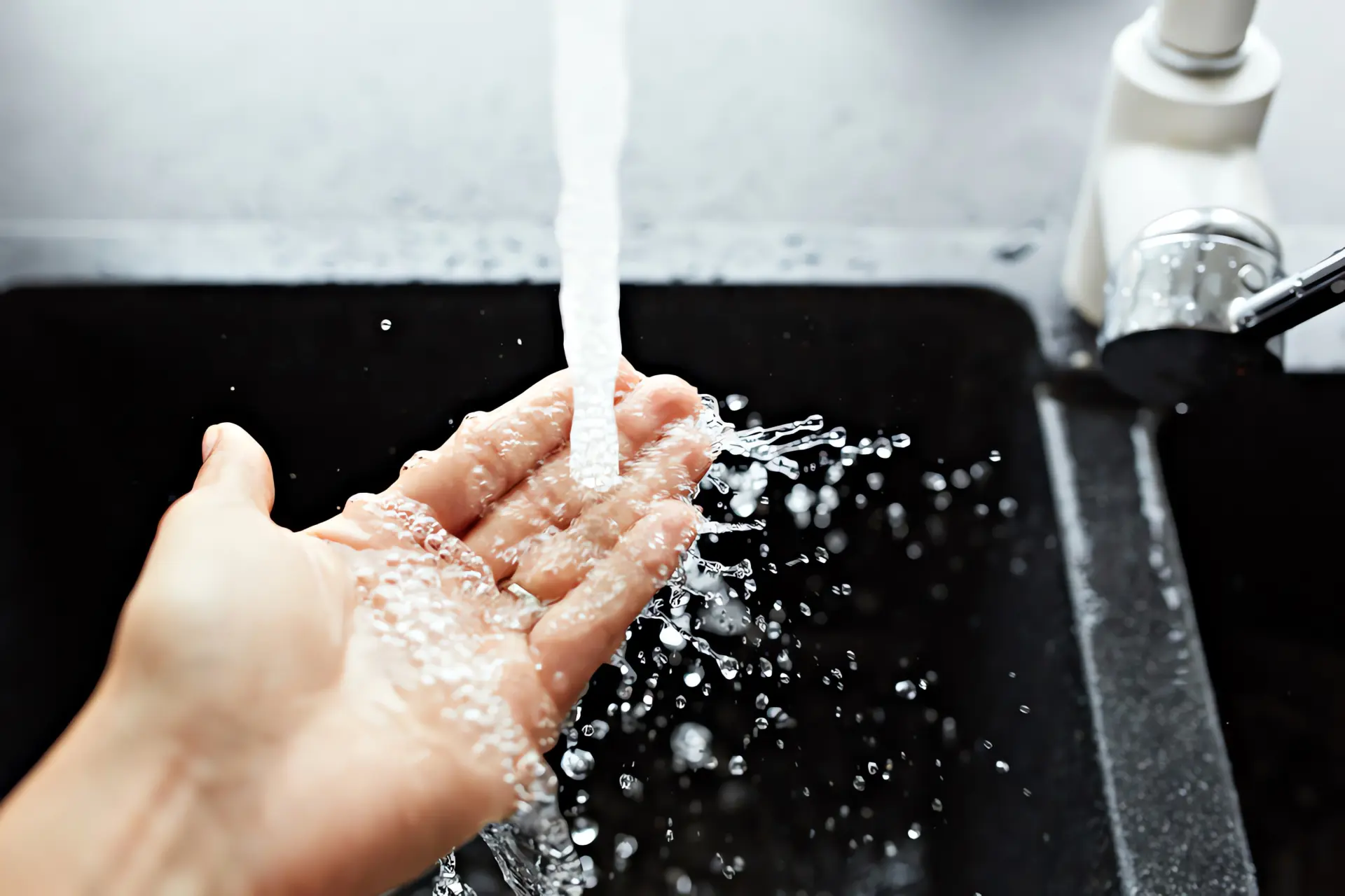 Standspeicher: Warmes Wasser fließt aus Wasserhahn über eine Hand. 