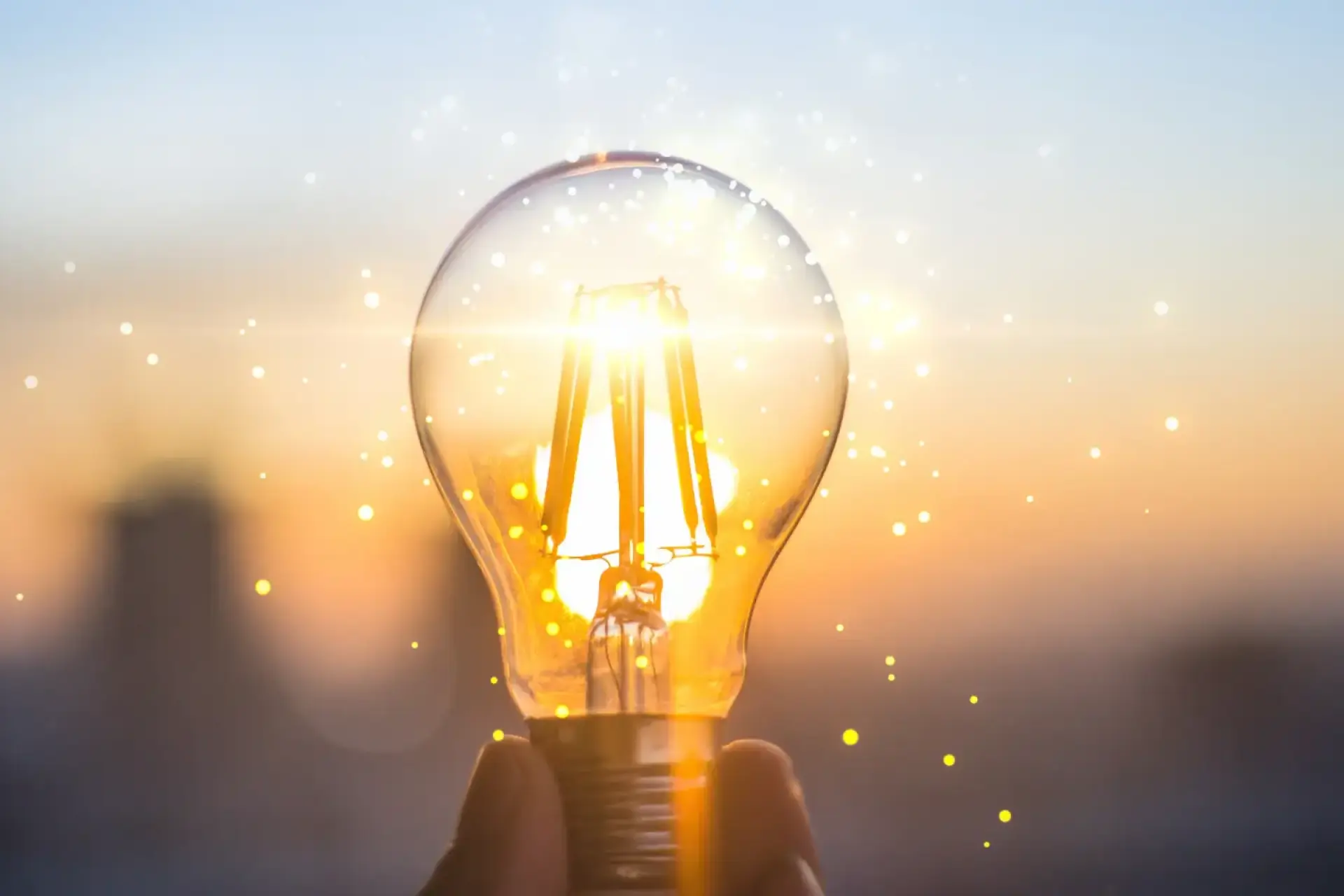 Stromverbrauch Wärmepumpe: Leuchtende Glühbirne wird in einer Hand gehalten