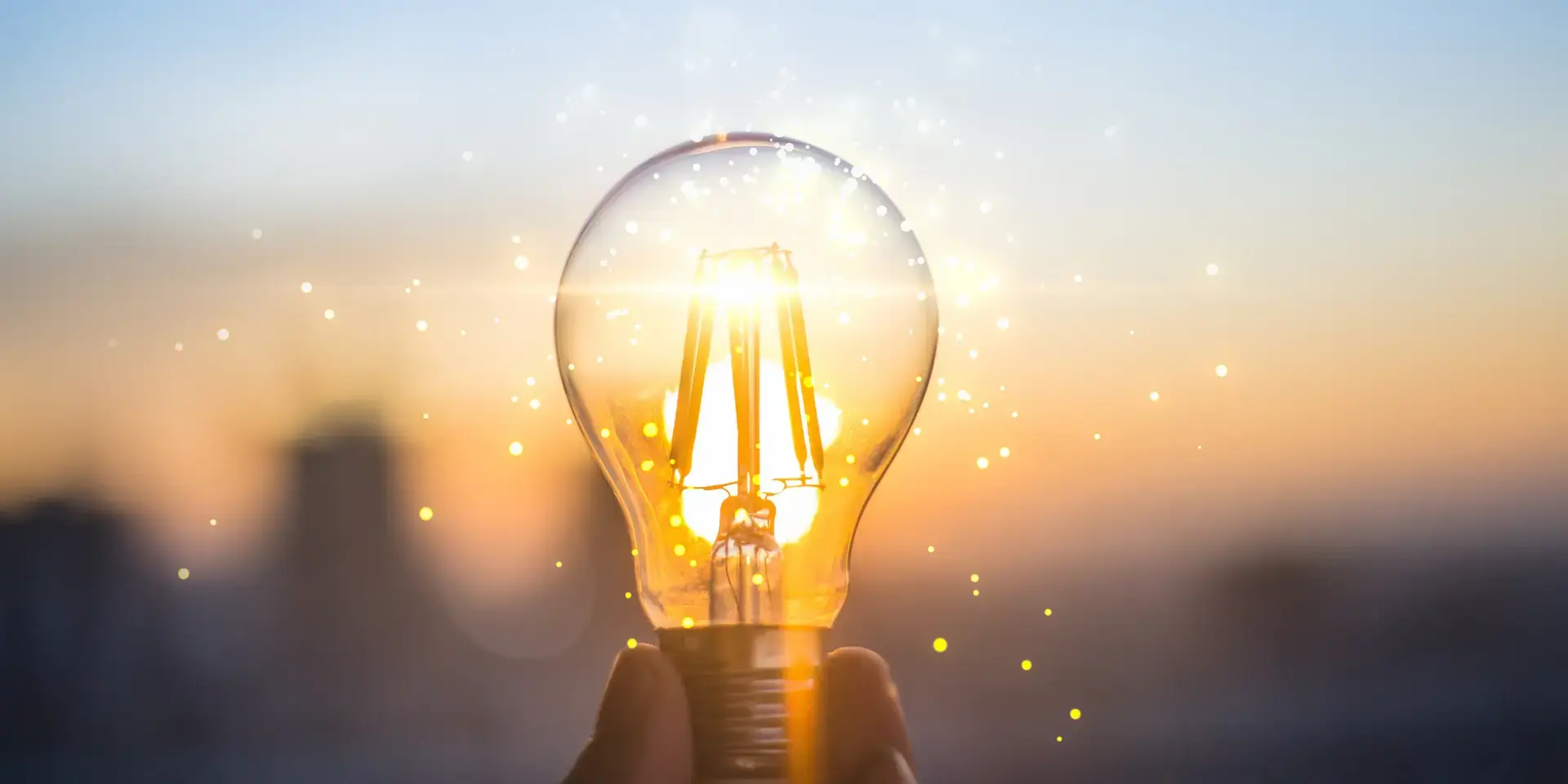 Stromverbrauch Wärmepumpe: Leuchtende Glühbirne wird in einer Hand gehalten