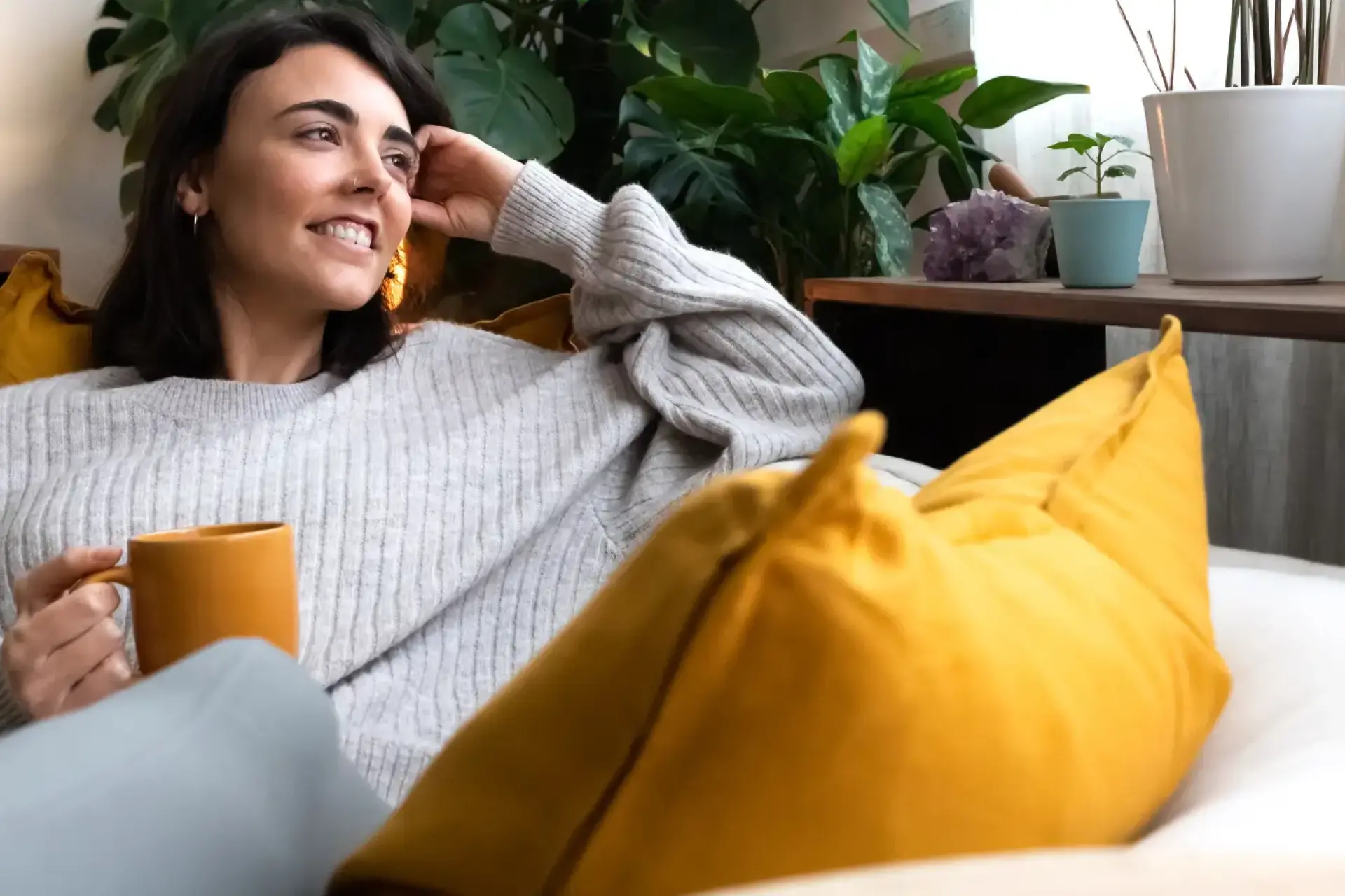 Vor und Nachteile Fernwärme: Lächende Frau auf dem Sofa