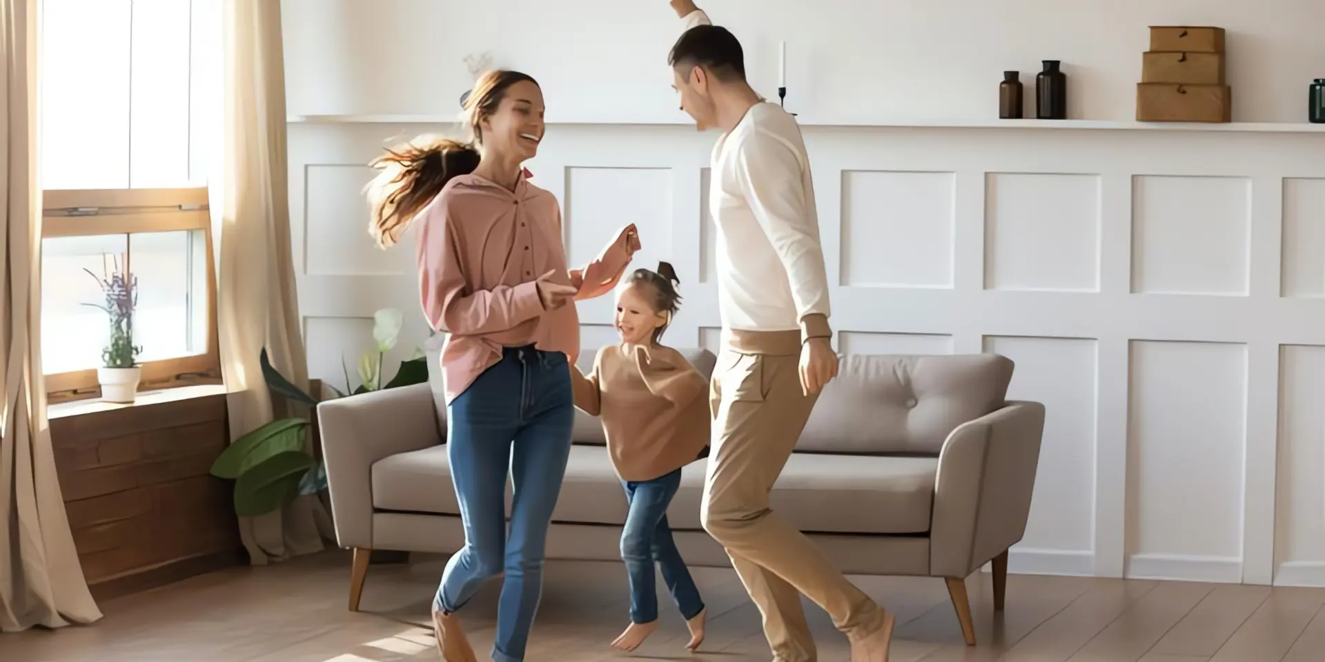 Glückliche Familie tanzt im Wohnzimmer mit Fußbodenheizung