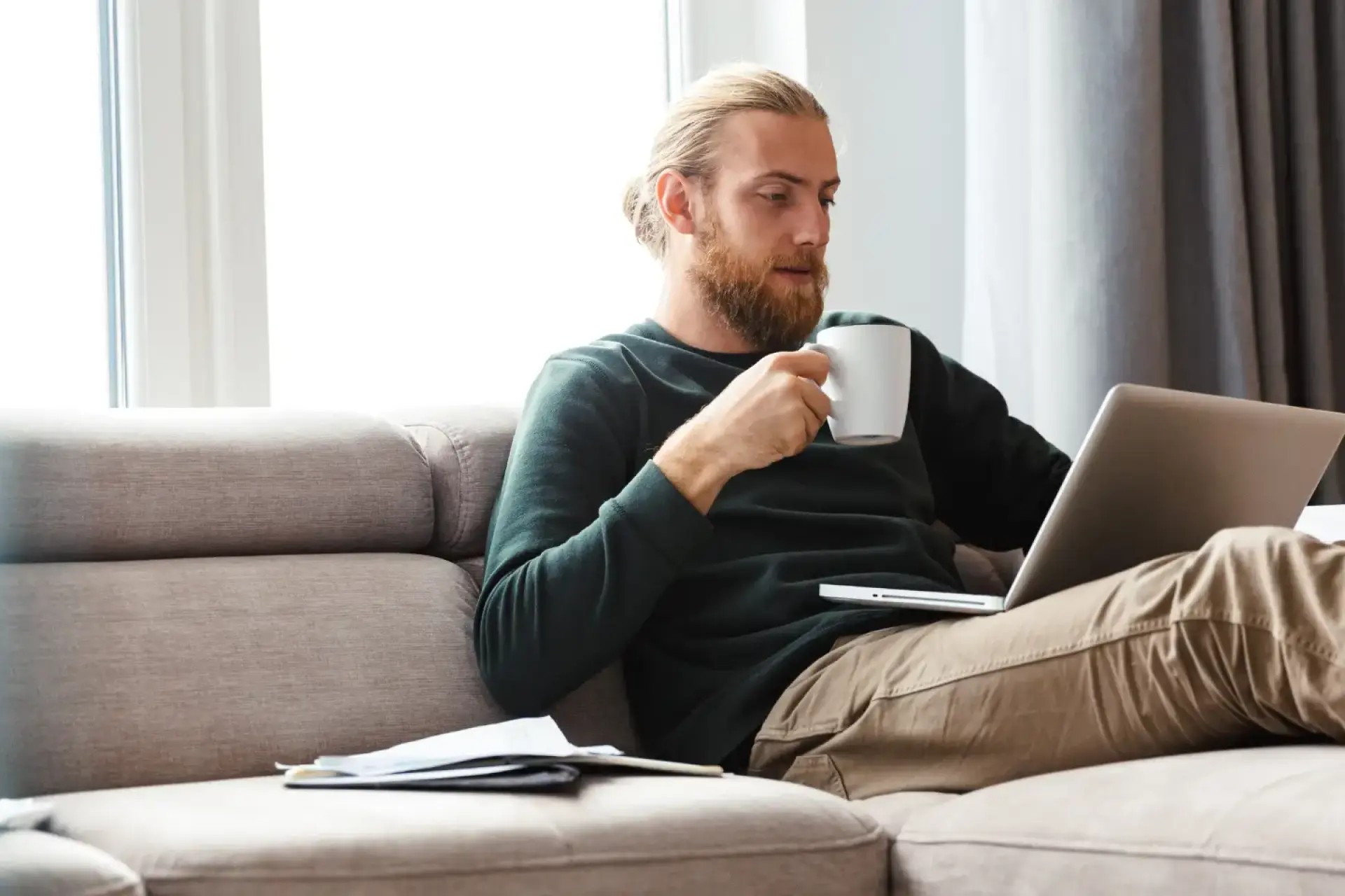 Wärmepumpe dampft: Mann sitzt auf dem Sofa und schaut auf den Laptop