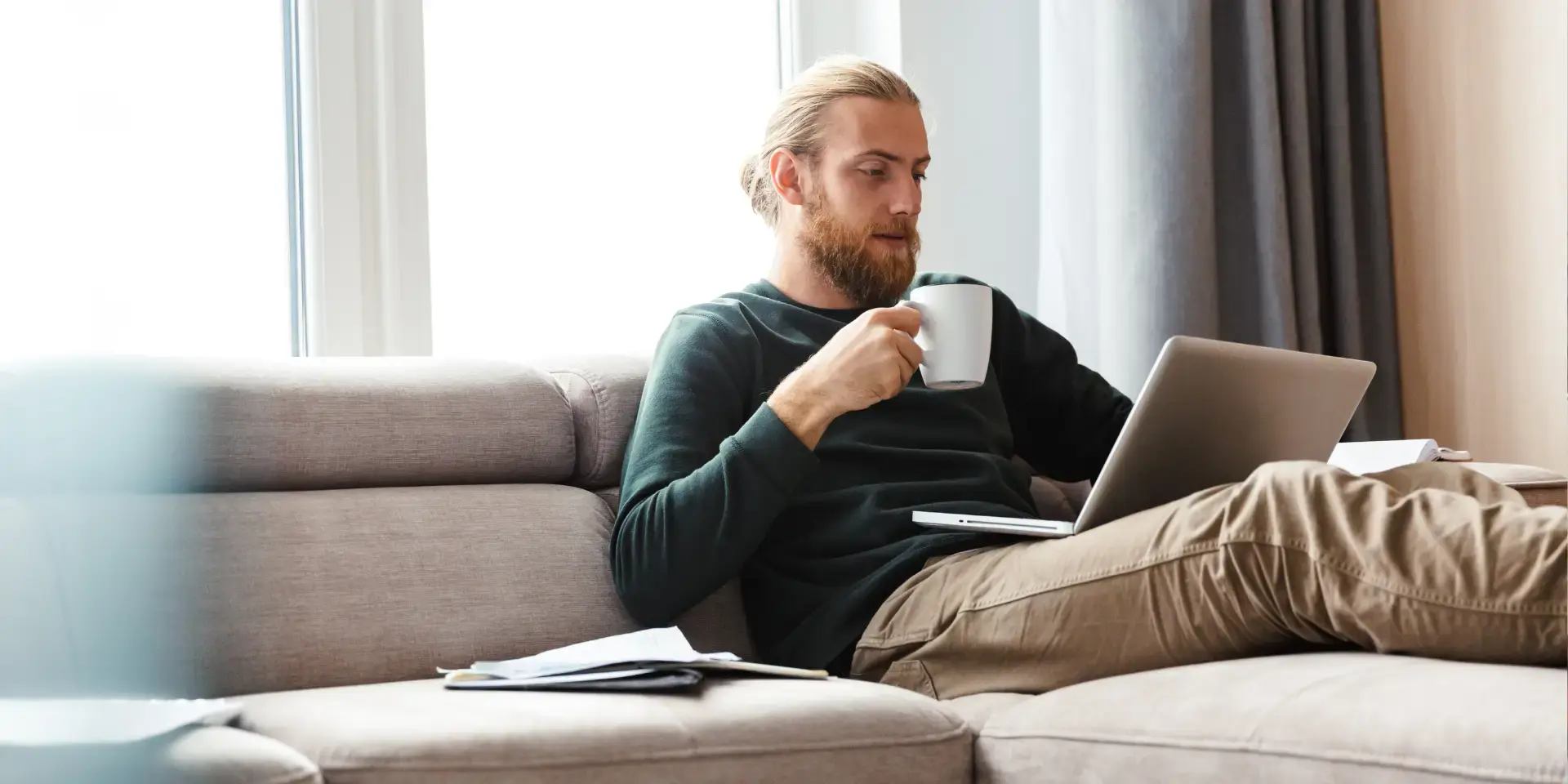Wärmepumpe dampft: Mann sitzt auf dem Sofa und schaut auf den Laptop