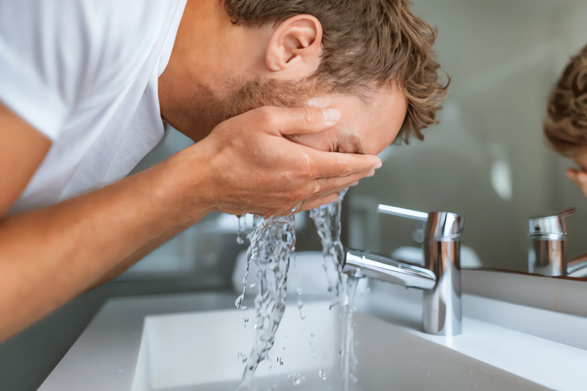 Warmwasserbereitung: Mann wäscht sein Gesicht mit Wasser